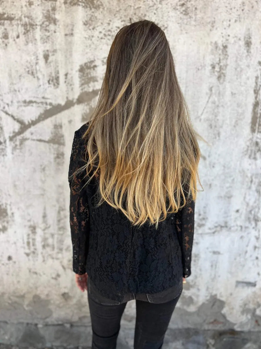 Vrouw draagt een zwarte kanten blazer met bloemendessin, perfect als licht jasje voor een stijlvolle look.