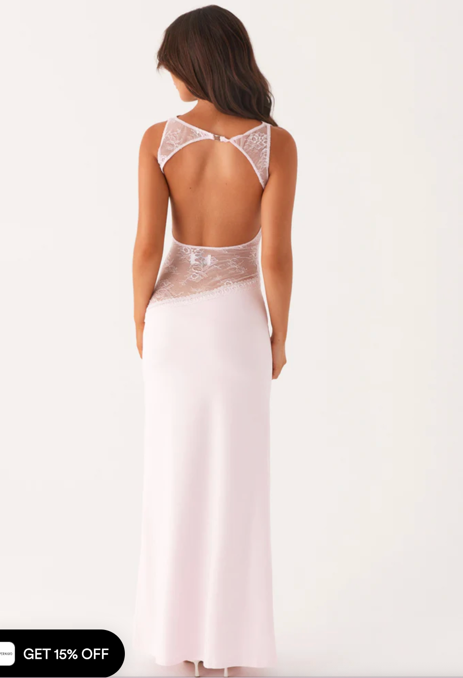 Model draagt een witte maxi-jurk met kanten inzetstuk rond de taille – elegante en moderne avondjurk in een verfijnd ontwerp.