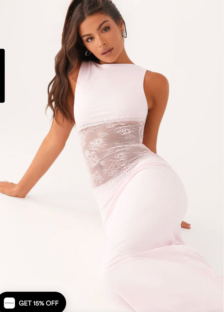 Model draagt een witte maxi-jurk met kanten inzetstuk rond de taille – elegante en moderne avondjurk in een verfijnd ontwerp.
