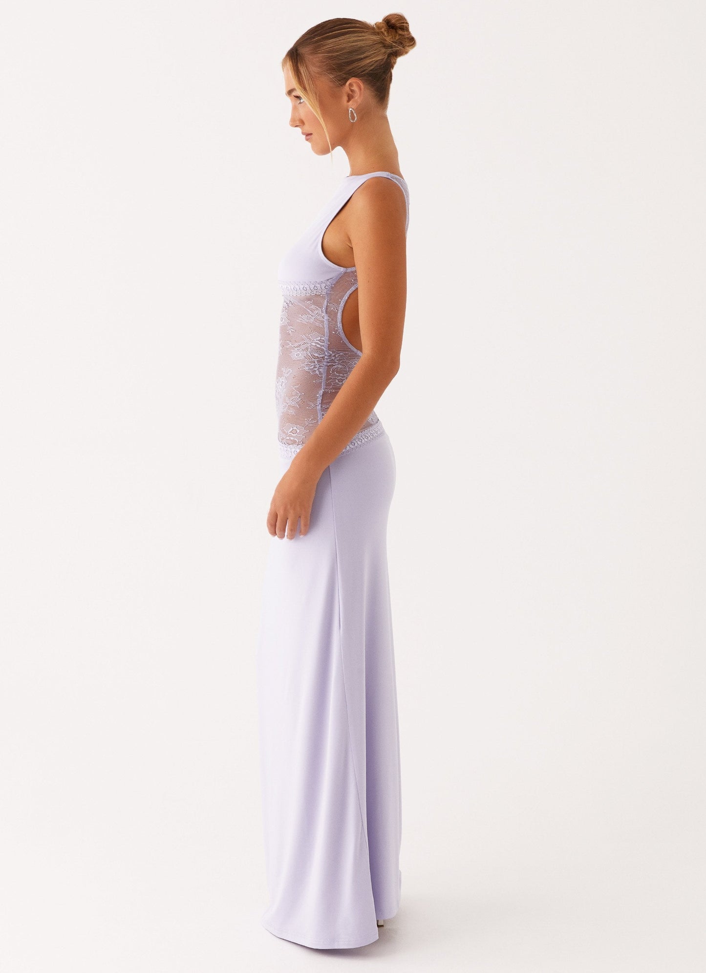 Model draagt een lila maxi-jurk met kanten inzetstuk rond de taille – elegante en moderne avondjurk in een verfijnd ontwerp.