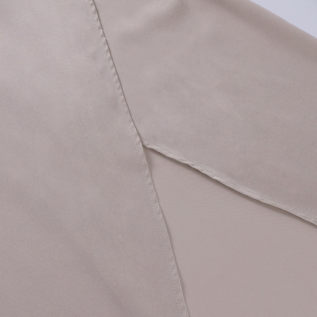 Model draagt een katoenen jurk met watervalhals en hoge split, ideaal voor een zomerse en stijlvolle look.
