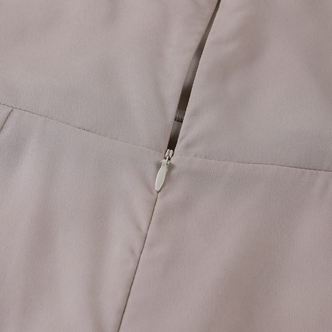 Model draagt een katoenen jurk met watervalhals en hoge split, ideaal voor een zomerse en stijlvolle look.