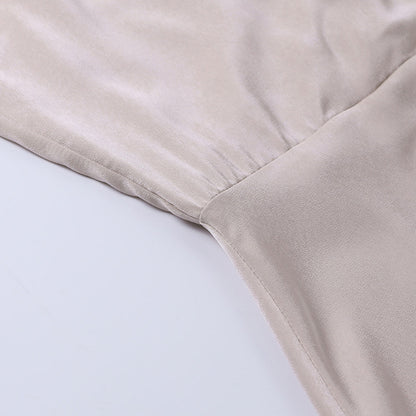 Model draagt een katoenen jurk met watervalhals en hoge split, ideaal voor een zomerse en stijlvolle look.
