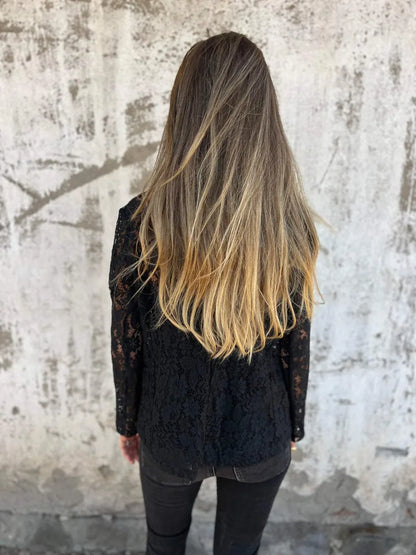 Vrouw draagt een zwarte kanten blazer met bloemendessin, perfect als licht jasje voor een stijlvolle look.