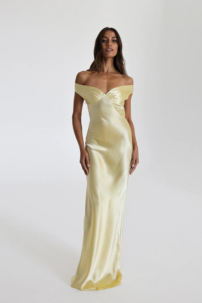 Model draagt een off shoulder satijnen maxi jurk met open rug, perfect voor formele avonden of gala’s.

