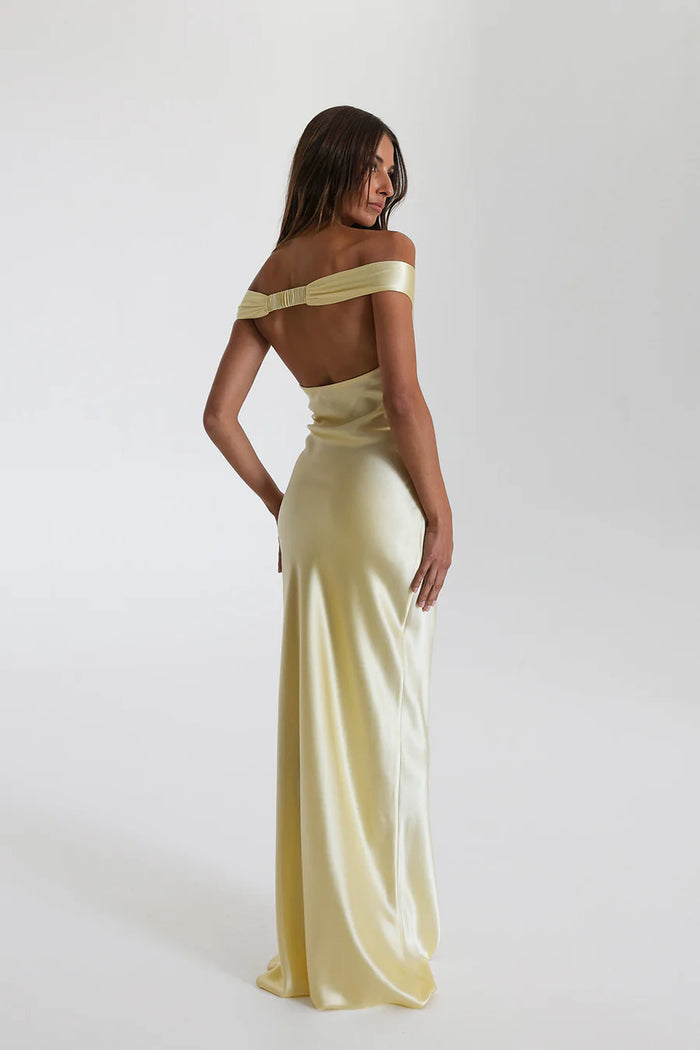 Model draagt een off shoulder satijnen maxi jurk met open rug, perfect voor formele avonden of gala’s.

