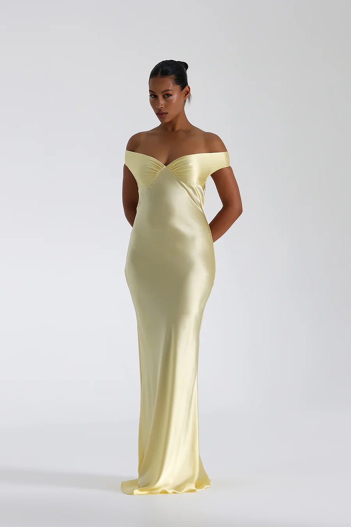 Model draagt een off shoulder satijnen maxi jurk met open rug, perfect voor formele avonden of gala’s.

