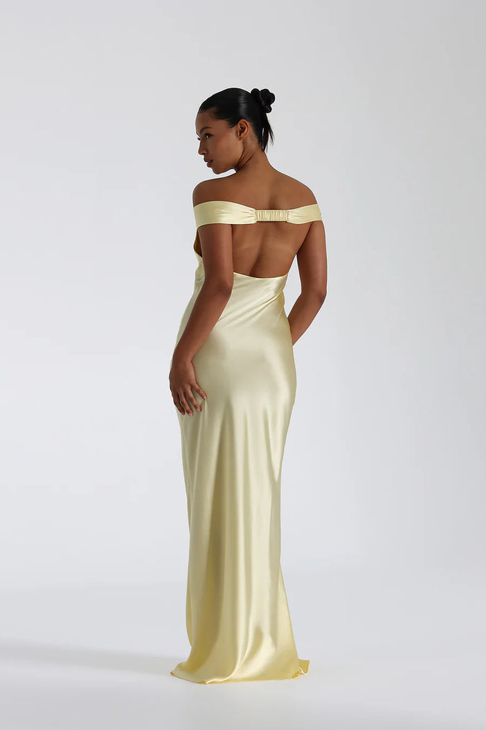 Model draagt een off shoulder satijnen maxi jurk met open rug, perfect voor formele avonden of gala’s.

