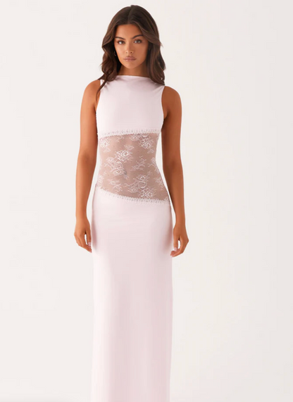 Model draagt een witte maxi-jurk met kanten inzetstuk rond de taille – elegante en moderne avondjurk in een verfijnd ontwerp.