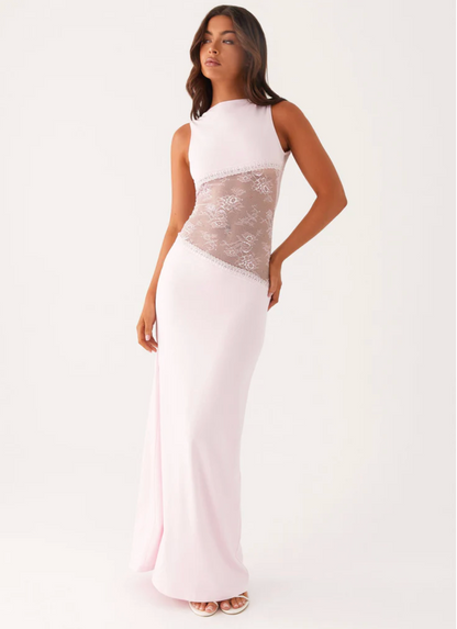 Model draagt een witte maxi-jurk met kanten inzetstuk rond de taille – elegante en moderne avondjurk in een verfijnd ontwerp.