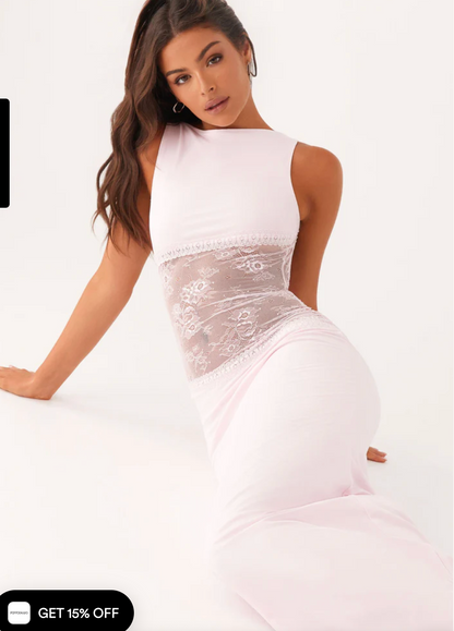 Model draagt een witte maxi-jurk met kanten inzetstuk rond de taille – elegante en moderne avondjurk in een verfijnd ontwerp.