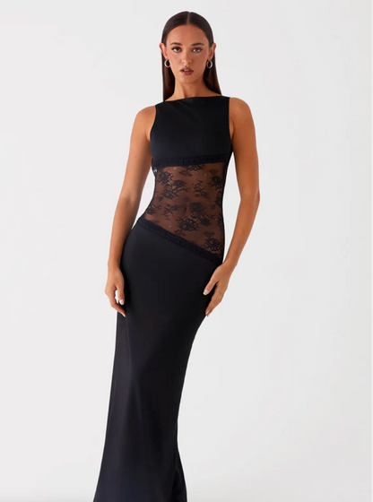 Model draagt een Zwarte maxi-jurk met kanten inzetstuk rond de taille – elegante en moderne avondjurk in een verfijnd ontwerp.
