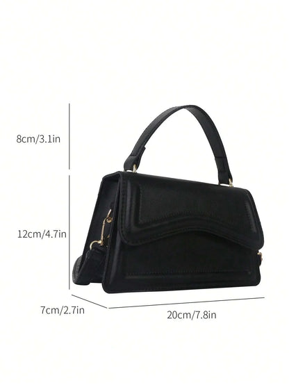 Zwarte minimalistische dames schoudertas met golvend design en verstelbare riem, close-up in hand








