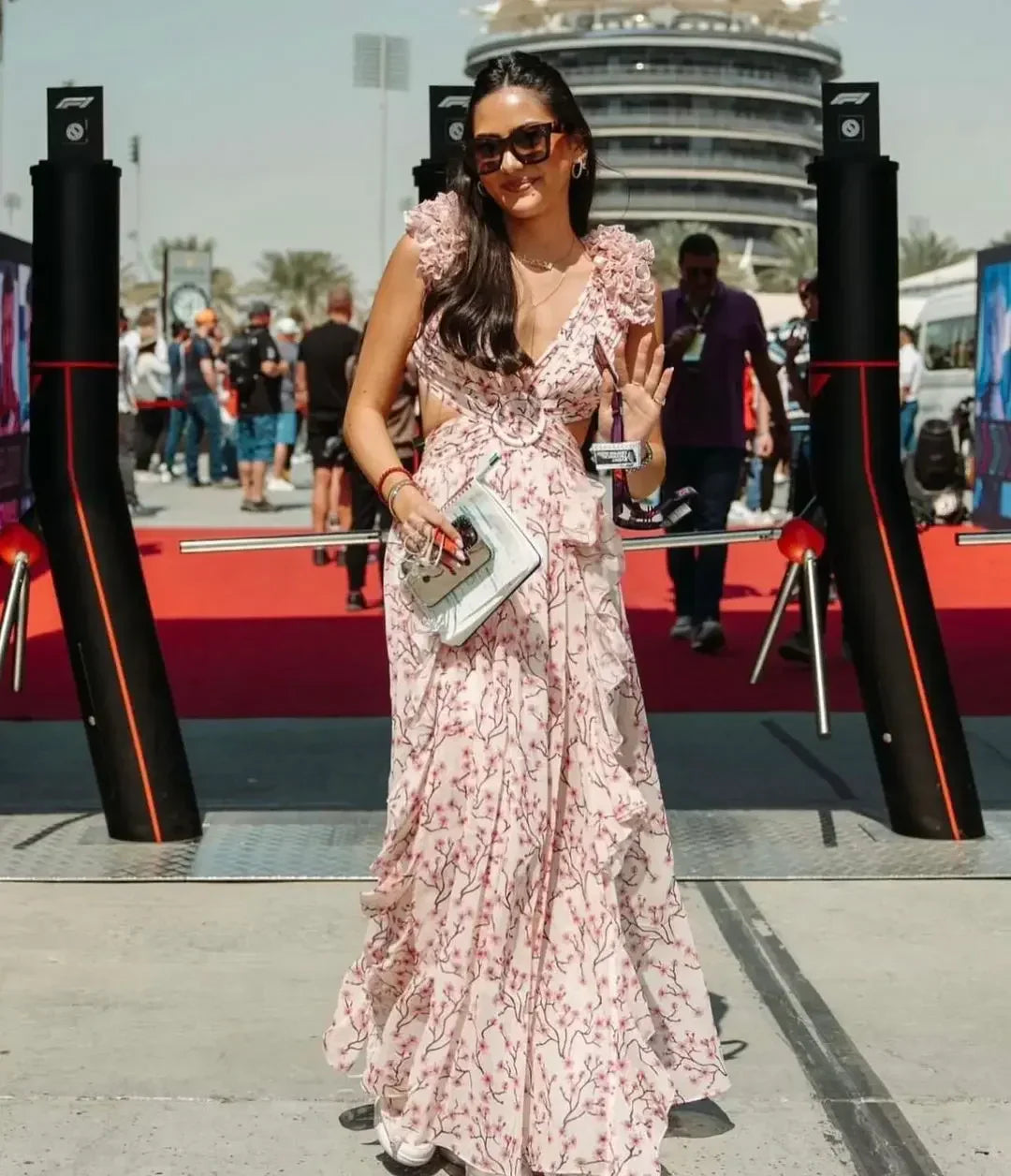 Vrouw draagt een romantische lange zomerjurk met roze bloemenprint, diepe V-hals en hoge split – perfect voor bruiloften of vakanties.